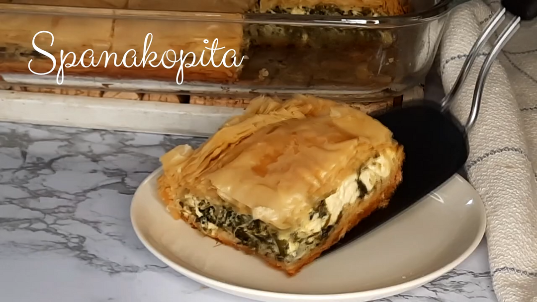 Spanakopita on a plate with a spatula, marble countertop background